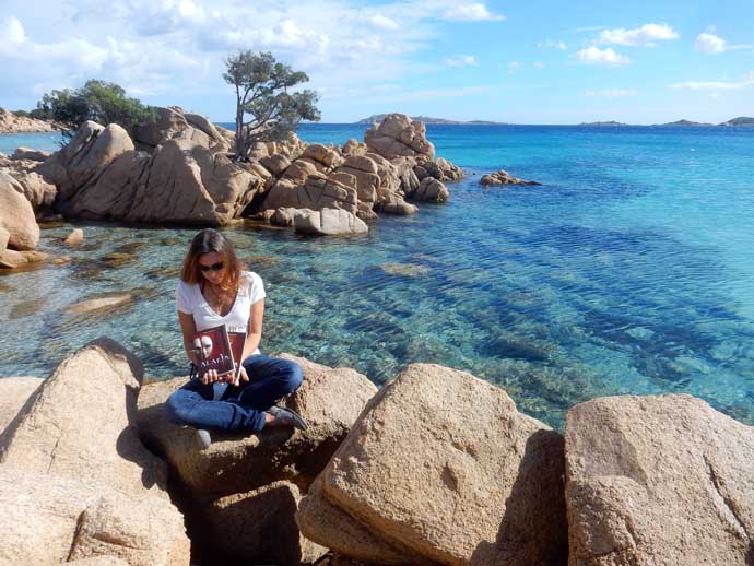 Anna Chillon  con i romanzi Alakim-Luce dalle Tenebre e Alakim-Le Regole del Gioco, seduta su uno scoglio in Sardegna